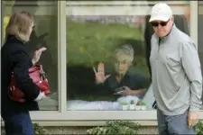  ?? TED S. WARREN — THE ASSOCIATED PRESS ?? Judie Shape, center, who has tested positive for the coronaviru­s, but isn’t showing symptoms, presses her hand against her window after a visit through the window and on the phone with her daughter Lori Spencer, left, and her son-in-law Michael Spencer, Tuesday, March 17, 2020, at the Life Care Center in Kirkland, Wash., near Seattle.