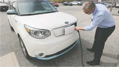  ?? DAN JANISSE ?? Dan Campeau of Gus Revenberg Kia in Windsor plugs in a Kia Soul electric vehicle. Sales of electric vehicles in Ontario have plummeted since the Ford government removed a rebate program last year.