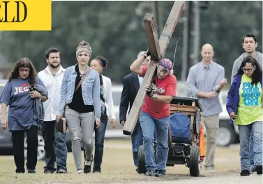  ?? ERIC GAY / THE ASSOCIATED PRESS ?? Stephen Hope carries a cross Sunday following a service for the victims of the Sutherland Springs, Texas, church shooting. “Rather than choose darkness as that young man did that day, we choose life,” said Pastor Frank Pomeroy.