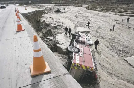  ?? DAVID PARDO/THE DAILY PRESS VIA THE ASSOCIATED PRESS FILE ?? Officials look over the scene at Interstate 15 in the Cajon Pass, Calif., where part of the freeway collapsed from, heavy rain, bring down a San Bernardino County firetruck and a big rig in February.