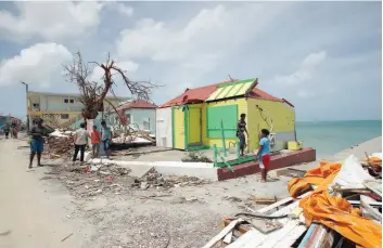  ?? — AFP ?? Residents stand beside the wreckage of their destroyed homes on the French Caribbean island of Saint Martin.