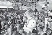  ?? JOHN VANBEEKUM Miami Herald File ?? Amir Hamza, a volunteer from Las Vegas, dances with a large yellow smiley face balloon on a raised platform beneath a canopy of inflatable pool floats at the 2009 Winter Party Festival on South Beach.