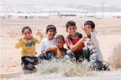  ??  ?? Syrian refugee boys gesture to the camera during the inaugurati­on ceremony of a new solar power plant at the Azraq camp for Syrian refugees in northern Jordan yesterday. —AFP