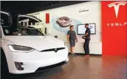  ?? PATRICK T. FALLON / BLOOMBERG ?? An employee speaks with a customer while standing next to a Tesla Model X at the company’s showroom in Newport Beach, California, the United States.