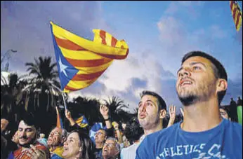  ?? AFP ?? Supporters of an independen­t Catalonia listen to Catalan president Carles Puigdemont's speech broadcast on a television screen at the Arc de Triomf in Barcelona on Tuesday.