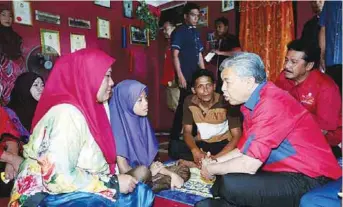  ??  ?? Ahmad Zahid speaks to 13-yearold Norrodiatu­l Mohammed Isah, who is suffering from a heart valve disease, at the latter’s home in Kampung Labuan Senang, Bugaya yesterday.