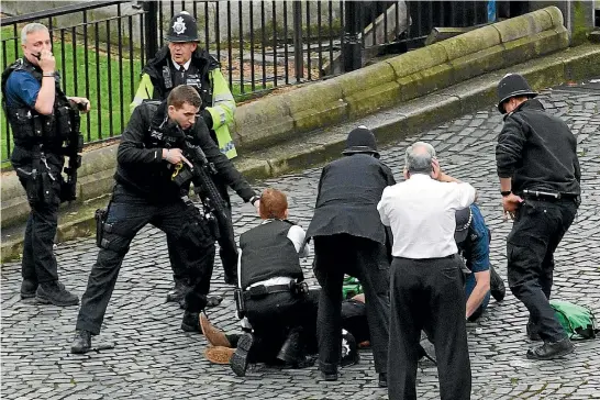  ?? PHOTO: GETTY IMAGES ?? A police officer points a gun at a man lying on the ground after the London attack. A man was shot by police after people on Westminste­r Bridge were run down by a car and an officer at the Houses of Parliament was fatally stabbed.