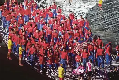  ??  ?? Malaysian athletes, led by Muhammad Hakimi Ismail, holding the Jalur Gemilang, followed by Chef de Mission Huang Ying How at the Commonweal­th Games in Gold Coast recently.