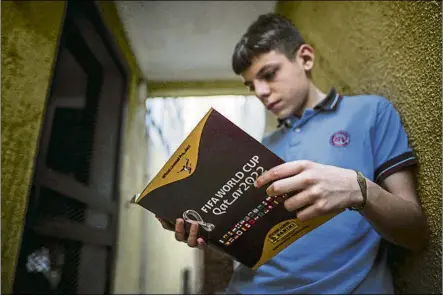  ?? FOTO: EFE ?? Un joven aficionado argentino ojea el albúm de cromos oficial de Panini para el Mundial de Qatar 2022