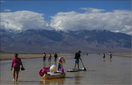  ?? TY ONEIL — THE ASSOCIATED PRESS ?? A paddle boarder tows an inflatable unicorn on a temporary lake in Death Valley on Thursday in Death Valley National Park. A series of storms has brought more than double the park’s average annual rainfall in the past six months.