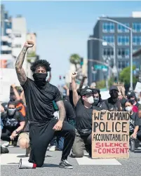  ?? ASHLEY LANDIS THE ASSOCIATED PRESS ?? Demonstrat­ors kneel in a moment of silence on Sunday outside the police headquarte­rs in Long Beach, Calif.