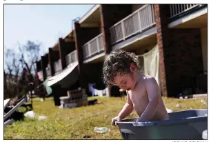  ?? AP/DAVID GOLDMAN ?? Gaige Williams, 2, cools off in a plastic container outside of the storm-damaged motel in Panama City, Fla., where he and his family live after being uprooted by Hurricane Michael.