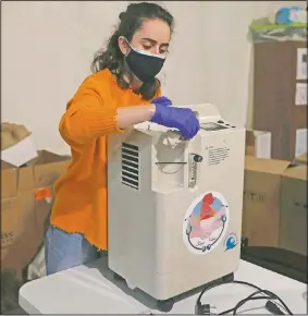  ??  ?? Gaelle Fenianos, a member of the Lebanese group Baytna Baytak, sanitizes an oxygen machine before it is delivered to patients in need in Beirut.