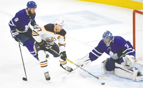  ?? DAN HAMILTON / USA TODAY SPORTS ?? Oilers forward Connor Mcdavid cuts between Maple Leafs goalie Frederik Andersen and defenceman Jake Muzzin in
NHL action Wednesday at Scotiabank Arena. The teams play each other again on Friday.