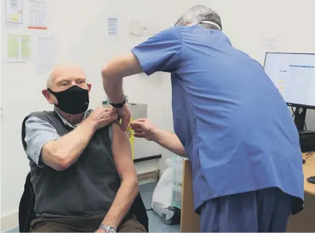  ??  ?? Pharmacist Andrew Hodgson administer­s a dose of the coronaviru­s vaccine to 82-year-old Robert Salt, at Andrew’s Pharmacy in Macclesfie­ld.