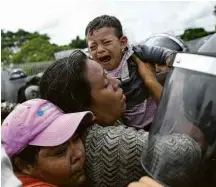  ??  ?? Migrantes ao lado da cerca que separa os dois países