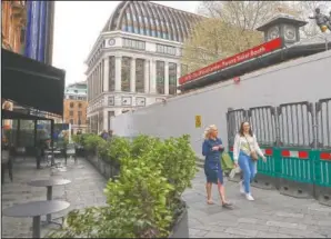  ??  ?? Pedestrian­s walk past the site of the official London Theater tcket booth normally selling last minute tickets to shows in London in Leicester Square.