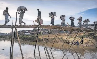  ?? [SERGEY PONOMAREV/THE NEW YORK TIMES] ?? Rohingya cross a makeshift bridge in the Kutupalong refugee camp outside Cox’s Bazar, Bangladesh. They are among 620,000 Rohingya Muslims, about two-thirds of the population that lived in Myanmar in 2016, who have fled a military campaign.