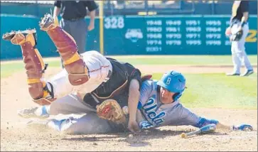  ?? Shotgun Spratling
Los Angeles Times ?? A HARD SLIDE by UCLA outfielder Ty Moore takes USC catcher Garrett Stubbs off his feet and knocks the ball free on a play at the plate in the sixth inning. The Bruins remain atop the Pac-12; USC is third.