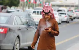  ?? ASSOCIATED PRESS ?? IN THIS DEC. 9 PHOTO, A MAN SMOKES Saudi Arabia. a cigarette as he looks at his mobile phone in Riyadh,