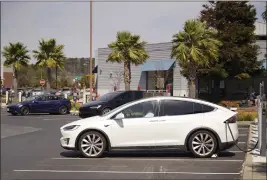  ?? ERIC RISBERG — THE ASSOCIATED PRESS ?? A man talks on his phone while sitting in his electric car at a Tesla charging station in Marin City on April 2, 2021.