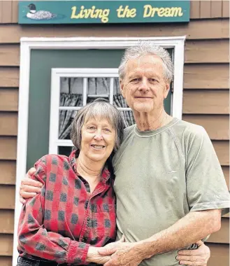  ?? TINA COMEAU ?? Joen and Robert Gingell stand outside their home in the Municipali­ty of Clare in southweste­rn Nova Scotia. The sign over the door reads ‘Living the dream’ because this is their dream home. Life has dealt them a difficult card though. Joen was recently diagnosed with a brain tumor. She was given five months to live.