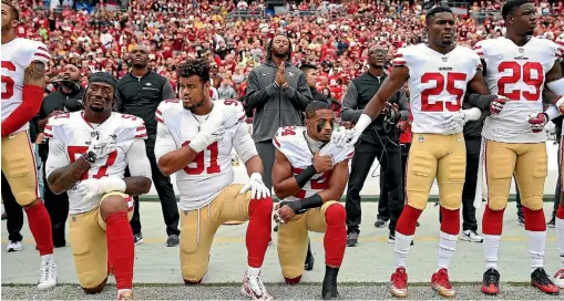  ?? PATRICK SMITH/ GETTY IMAGES ?? San Francisco 49ers players (from left) Eli Harold, Arik Armstead kneel while holding their hands over their chest during the US national anthem before playing against the Washington Redskins.