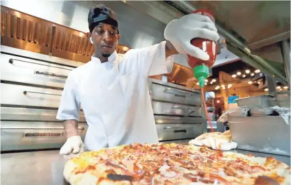  ?? JOE RONDONE/THE COMMERCIAL APPEAL ?? Aaron Warren prepares the daily pies with Sriracha sauce at Aldo’s Pizza on March 18. Aldo’s is offering in-house delivery and curbside pickup.