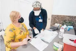  ?? MARY ALTAFFER/AP ?? A nurse goes over paperwork with mosque member Zejreme Rodoncic after giving her a COVID-19 vaccine Thursday in the Staten Island borough of New York.