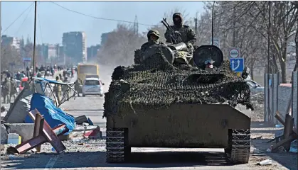  ?? ?? INVADERS: Pro-Russian troops drive through the chaos of the battered port city of Mariupol in southern Ukraine