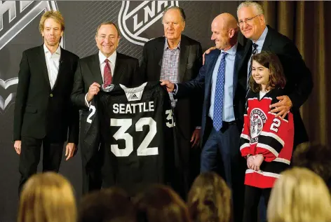  ?? STEPHEN B. MORTON/THE ASSOCIATED PRESS ?? NHL commission­er Gary Bettman, second from left, displays a jersey after announcing that Seattle had been awarded the league’s 32nd franchise on Tuesday. Joining Bettman at the ceremony are team owners Jerry Bruckheime­r, left, David Bonderman and David Wright, team president Tod Leiweke, and Washington Wild youth hockey player Jaina Goscinski.