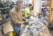  ??  ?? Sarmad Eskandar, left, and Mustpha Damen work on electrical components at the Howard McCray’s commercial refrigerat­ion manufactur­ing facility in Philadelph­ia this month.