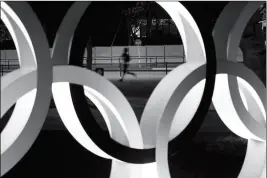  ?? ASSOCIATED PRESS ?? IN THIS MARCH 30 FILE PHOTO, a man jogs past the Olympic rings in Tokyo.