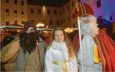  ?? Fotos: Berthold Veh ?? Ein strahlende­s Christkind: Rosalie Hungbaur bringt zusammen mit Nikolaus Markus Hirner und Knecht Ruprecht Christian Remmele nicht nur Bonbons und Nüsse auf den Dillinger Christkind­lesmarkt, sondern auch eine Menge Herzlichke­it. Zur Eröffnung am Freitagabe­nd kamen trotz widrigen Wetters Scharen von Besuchern.