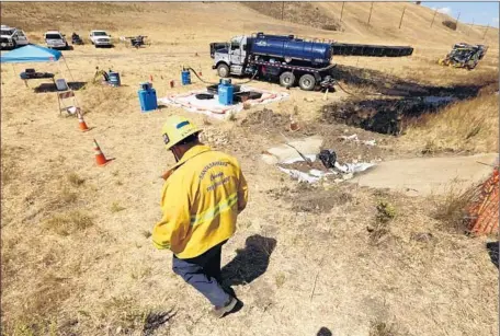  ?? Al Seib ?? MIKE ELIASON of the Santa Barbara County Fire Department walks near the oil spill site a day after the May 19 pipeline rupture at Refugio State Beach. As much as 101,000 gallons of crude spilled, about 21,000 gallons of that f lowing into the Pacific...