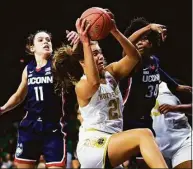  ?? Michael Caterina / Associated Press ?? Notre Dame’s Maddy Westbeld (21) comes down with a rebound as UConn’s Ayanna Patterson (34) and Lou Lopez Senechal (11) defend during the first half Sunday.