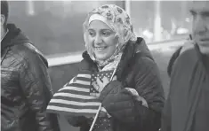  ?? SCOTT OLSON, GETTY IMAGES ?? Syrian refugee Baraa Haj Khalaf clutches an American flag after arriving with her family in Chicago on Feb. 7.