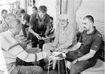  ??  ?? Iraqis drink tea at a cafe in the destroyed Old City of Mosul, Iraq. — Reuters photo