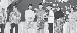  ??  ?? TERIMA KASIH: Ripin menyampaik­an kupon Pesta Tanjong kepada pelajar Penan dan Punan. Kelihatan sama, Hasimah (kanan) dan Mohd Sabri (kiri).