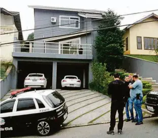  ?? Divulgação/polícia Civil ?? Policiais na frente da casa de um dos suspeitos, com carros de luxo ao fundo, em Arujá (Grande SP); sete membros de quadrilha foram presos em operação