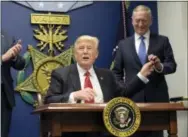  ?? THE ASSOCIATED PRESS ?? President Donald Trump, left, hands Defense Secretary James Mattis, right, a pen after he signed an executive action on rebuilding the military during an event at the Pentagon in Washington on Friday.