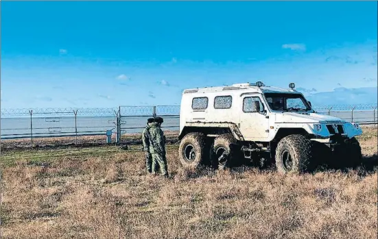  ?? TASS / GETTY ?? Dos militares rusos junto a la valla de separación, equipada con sensores de movimiento­s y circuitos de televisión