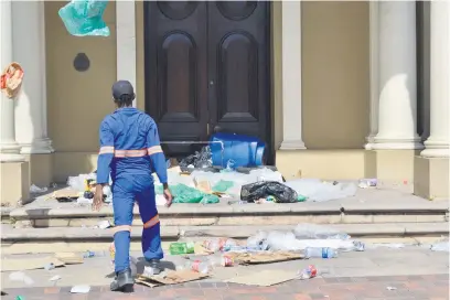  ?? Picture: Thamsanqa Mbovane ?? TRASHING THE PLACE. A worker from the mayoral cleaning and greening programme throws rubbish in front of Gqeberha City Hall on Wednesday, during a protest over wages.