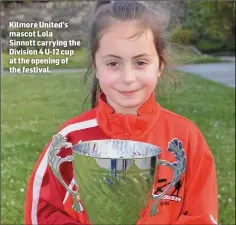  ??  ?? Kilmore United’s mascot Lola
Sinnott carrying the Division 4 U-12 cup at the opening of the festival.