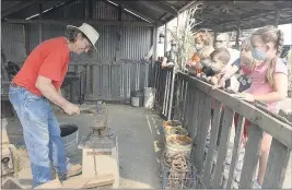  ??  ?? Blacksmith, Steve Taylor demonstrat­es his craft to a group of young visitors to Silveyvill­e Pumpkin Farm in Dixon.