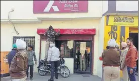  ??  ?? Police making inquiries outside the Axis Bank branch in Naurangaba­d village The branch was looted by