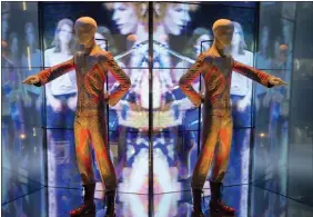  ?? Photos and text from The Associated Press ?? A reflection of the costume that David Bowie wore as Ziggy Stardust on tour and during a performanc­e of “Starman” on British pop music show “Top of The Pops” is shown as part of a retrospect­ive David Bowie exhibition, entitled “David Bowie Is” at the V&A Museum in west London in 2013.