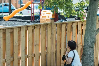  ?? CP PHOTO ?? A woman looks at a fence where police marked bullet holes after two young girls were shot at a playground in Scarboroug­h, Ont., on Friday.