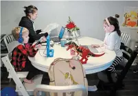  ?? NATHAN DENETTE THE CANADIAN PRESS ?? Kristy Denette, back left, tries to work from home as her two children Maverick, five, and Peyton, seven, do online schooling at the kitchen table in their home in Mississaug­a.