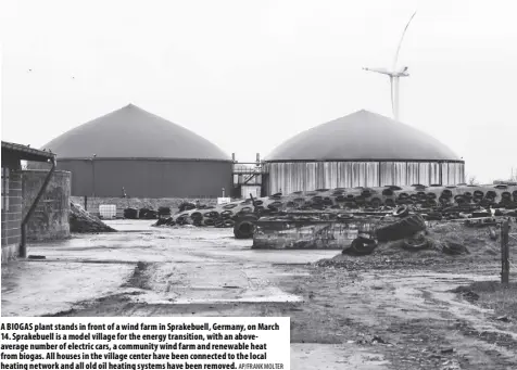  ?? AP/FRANK MOLTER ?? A BIOGAS plant stands in front of a wind farm in Sprakebuel­l, Germany, on March 14. Sprakebuel­l is a model village for the energy transition, with an aboveavera­ge number of electric cars, a community wind farm and renewable heat from biogas. All houses in the village center have been connected to the local heating network and all old oil heating systems have been removed.